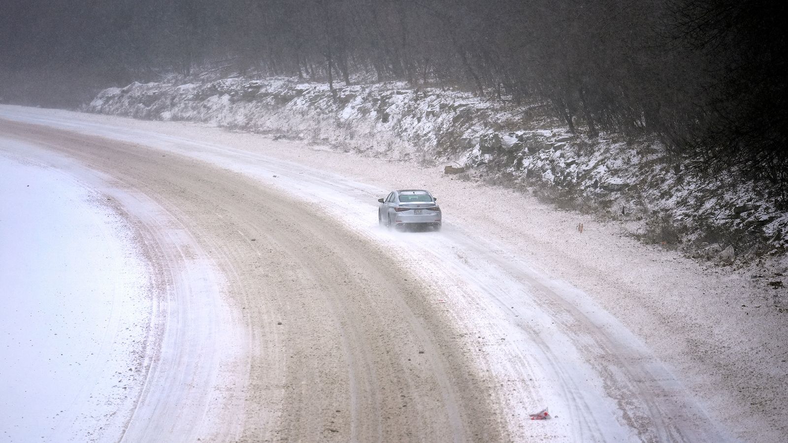 Photo of a car driving on a snow-covered road in St. Louis, MO.